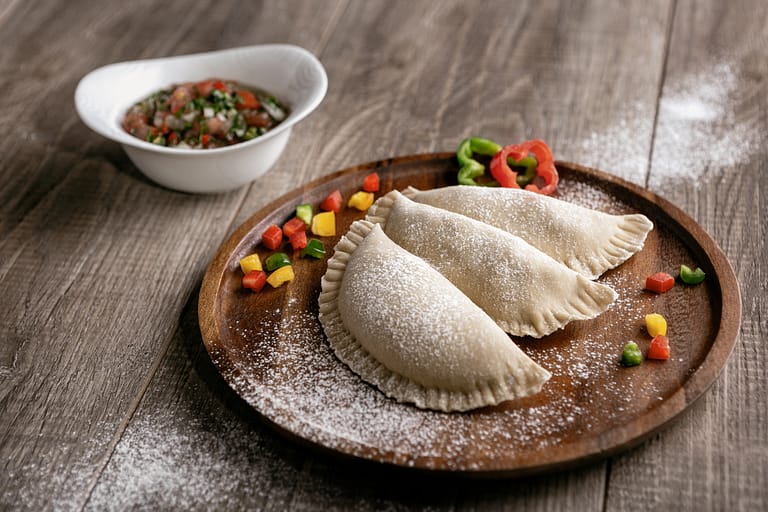 Uncooked Empanadas in a plate with cut vegetables 